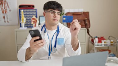 Genç İspanyol doktor akıllı telefon ve kredi kartıyla klinikten alışveriş yapıyor.