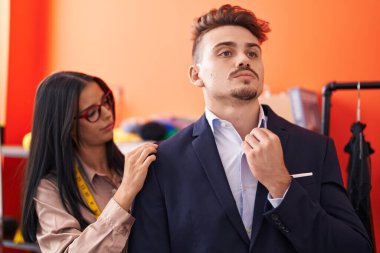 Erkek ve kadın atölyedeki müşterinin terzi ceketini dikiyor.