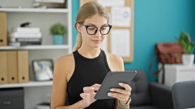 Ofiste dokunmatik ped kullanan genç sarışın bir iş kadını.