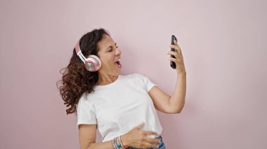 Orta yaşlı İspanyol bir kadın müzik dinliyor. Pembe arka planda gitar jesti yapıyor.