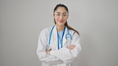 Genç, güzel İspanyol kadın doktor, gülümsüyor. Kollarını kavuşturup, izole beyaz arka planda hareketler yapıyor.