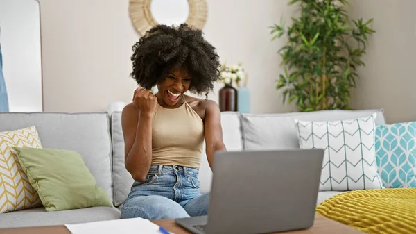 Mujer Afroamericana Usando Laptop Sentada Sofá Celebrando Casa —  Fotos de Stock