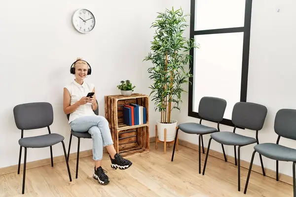 Junge Blonde Frau Sitzt Mit Smartphone Und Kopfhörer Auf Stuhl — Stockfoto