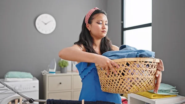 洗濯室で深刻な顔をした服でバスケットを持っている若い中国人女性 — ストック写真