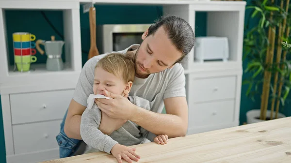 Father and son sitting on table cleaning face at dinning room