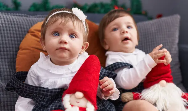 Kanepede Oturup Noel Baba Oyuncağıyla Oynayan Iki Sevimli Bebek — Stok fotoğraf
