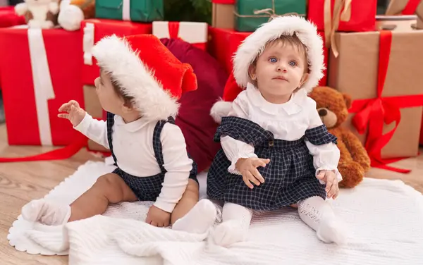 自宅でクリスマスプレゼントで床に座っている2人の愛らしい赤ちゃん — ストック写真