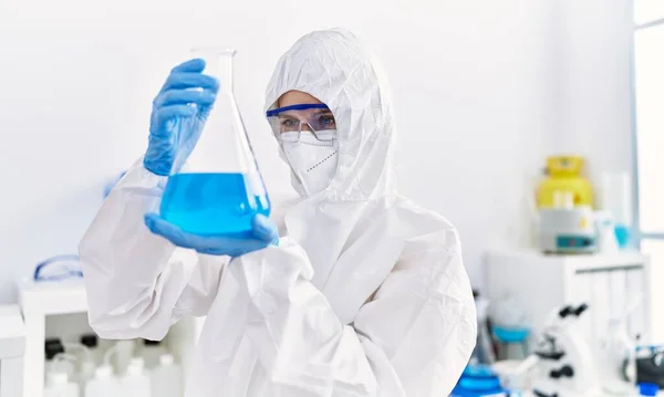 Young blonde woman scientist wearing security uniform holding test tube at laboratory