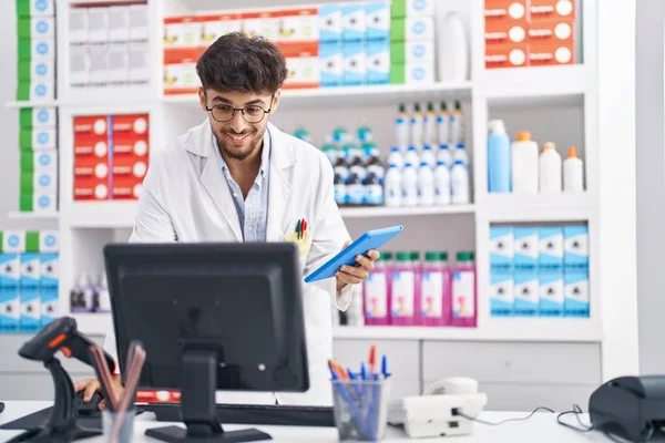 Young arab man pharmacist using computer and touchpad at pharmacy
