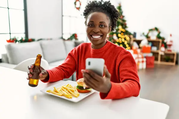 아프리카 미국인 집에서 크리스마스 탁자에 스마트폰으로 햄버거를 있습니다 — 스톡 사진