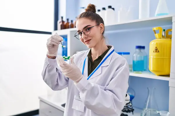 Young woman scientist holding pills at laboratory
