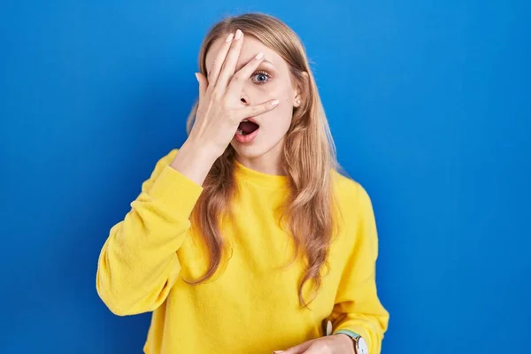Jonge Blanke Vrouw Staan Blauwe Achtergrond Gluuren Shock Bedekking Gezicht — Stockfoto