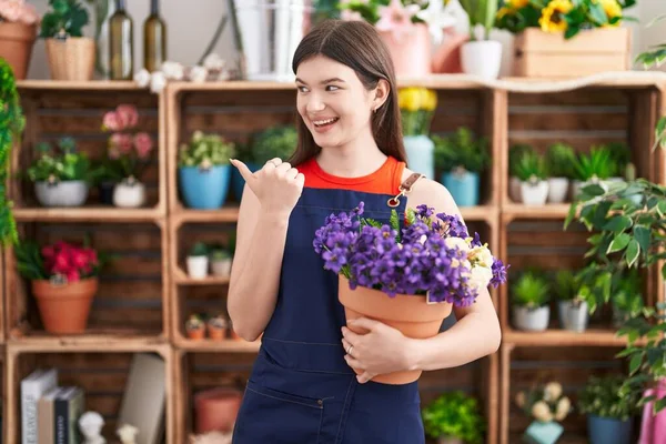 Joven Mujer Caucásica Trabajando Floristería Sosteniendo Maceta Con Flores Apuntando —  Fotos de Stock