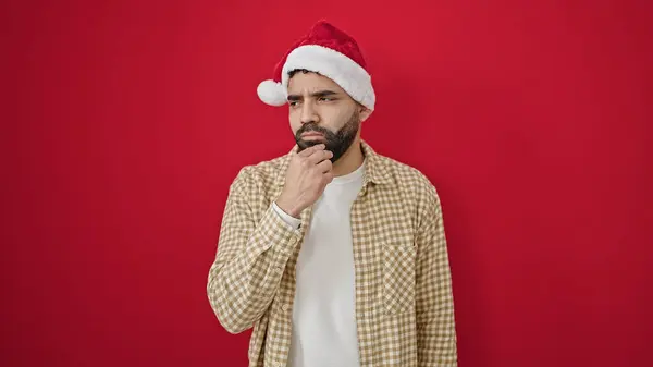 Junger Hispanischer Mann Mit Weihnachtsmütze Und Zweifelndem Gesichtsausdruck Vor Isoliertem — Stockfoto