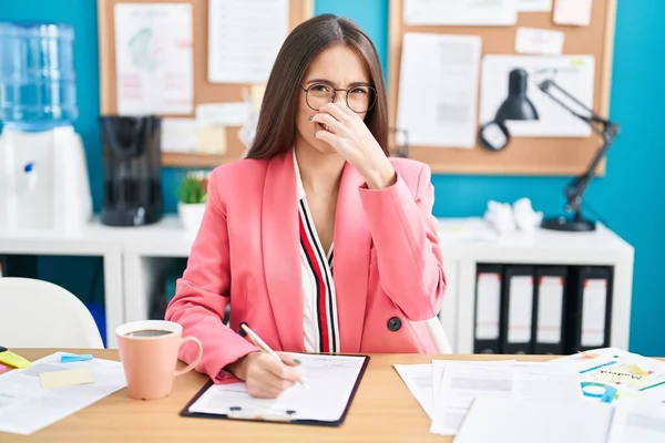 若いヒスパニック系の女性は オフィスで眼鏡を着用し 鼻の上に指で息を保持し 臭いや嫌な 耐え難い匂いのにおいが働く 臭いが悪い — ストック写真