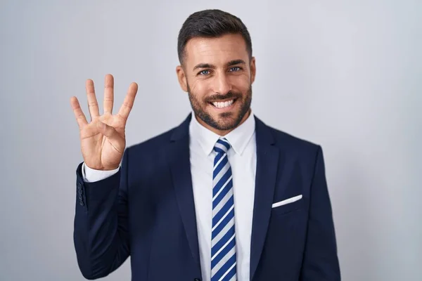 ハンサムなヒスパニックの男性は 自信と幸せに微笑んでいる間 スーツとネクタイを示し 指番号4を指で指摘しています — ストック写真