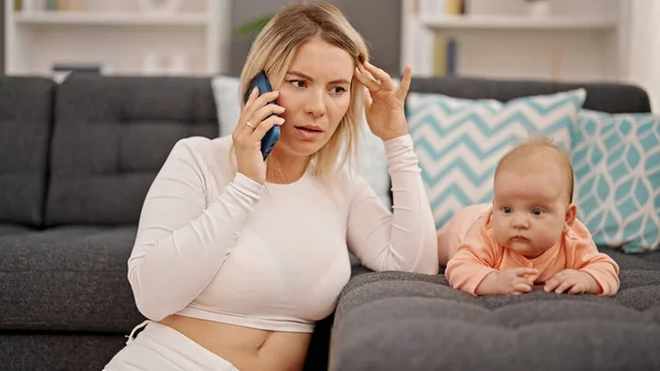 Mother and daughter talking on smartphone sitting together at home
