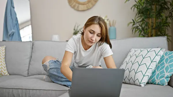 若いです女性使用してノートパソコン上のソファに家に座って — ストック写真