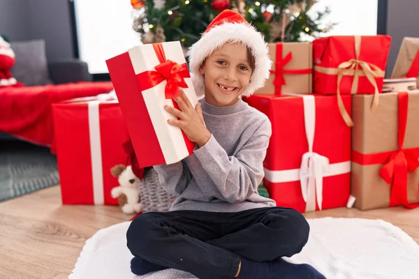 可爱的小男孩拿着圣诞礼物坐在家里的地板上 — 图库照片
