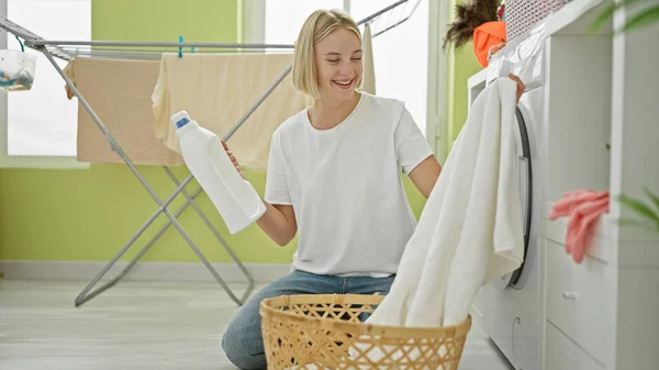 Joven Mujer Rubia Sosteniendo Toalla Limpia Botella Detergente Sonriendo Lavandería — Foto de Stock