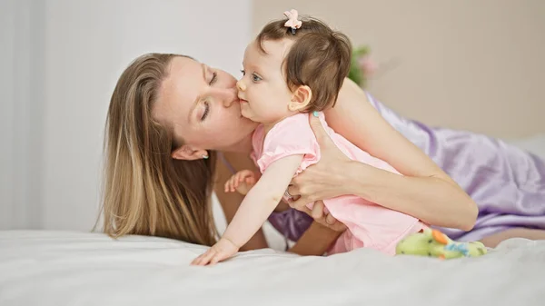 Mother and daughter lying on bed kissing at bedroom