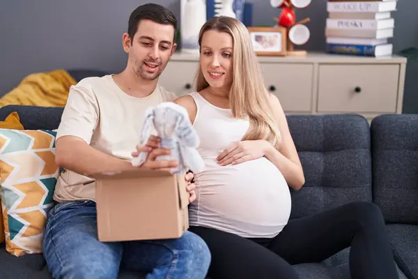 Man and woman couple expecting baby unpacking rabbit doll at home