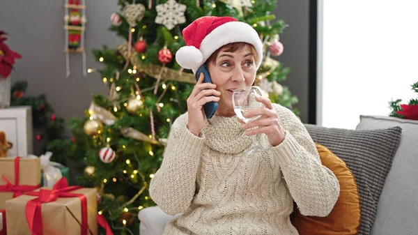 Dojrzała Latynoska Kobieta Rozmawiająca Przez Telefon Przez Choinkę Pijąca Wino — Zdjęcie stockowe