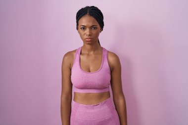 Saçları örgülü Afro-Amerikan kadın pembe arka plan kuşkucu ve gergin, sorun yüzünden üzgün. negatif kişi. 