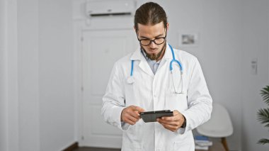 Genç İspanyol doktor klinik bekleme odasında dokunmatik ped kullanıyor.