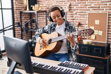Müzik stüdyosunda klasik gitar çalan Afrikalı Amerikalı kadın müzisyen.