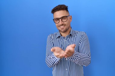 Elleri avuçlarında gülümseyen ve el hareketi yapan sakallı İspanyol bir adam. Bekleme ve koruma 