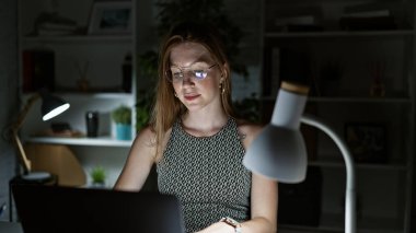 Genç sarışın iş kadını ofiste çalışırken laptop kullanıyor.