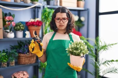 Young hispanic woman working at florist shop skeptic and nervous, frowning upset because of problem. negative person. 