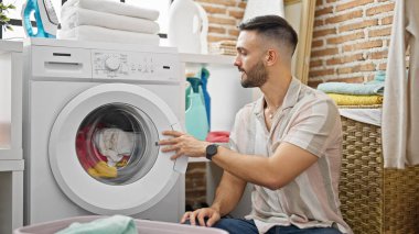 Çamaşırhanede çamaşır yıkayan İspanyol genç adam.