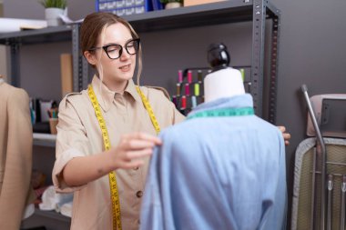 Beyaz kadın terzi atölyede kendine güvenen ölçü gömleği giyiyor.