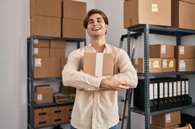 Young caucasian man ecommerce business worker hugging package at office