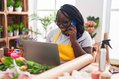 Çiçekçide bilgisayarla konuşan Afrikalı Amerikalı çiçekçi kadın.