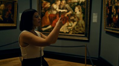 Güzel İspanyol bir kadın sanat galerisini ziyaret ediyor. Viyana 'daki Sanat Müzesi' nde akıllı telefonuyla fotoğraf çekiyor.