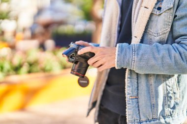 Young hispanic man using professional camera at park