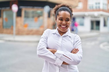 Sokakta kollarını kavuşturmuş Afro-Amerikalı bir kadın.