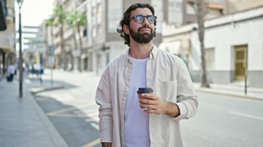 Genç İspanyol adam sokakta kahve içiyor.