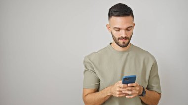 Genç İspanyol adam izole edilmiş beyaz arka plan üzerinde akıllı telefon kullanıyor.