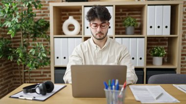 Young hispanic man business worker using laptop working at office