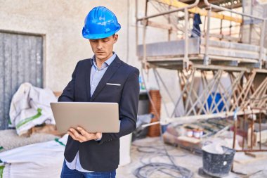 Young man architect using laptop at street
