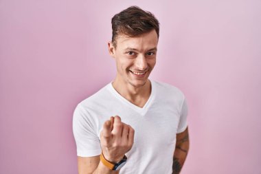 Pembe arka planda dikilen beyaz bir adam buraya el kol hareketi yaparak mutlu bir şekilde karşılamaya ve gülümsemeye davet ediyor. 