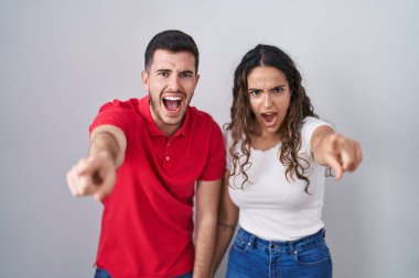 Genç İspanyol çift, izole edilmiş arka planda dikiliyor. Kameraya kızgın ve sinirli olduklarını gösteriyorlar. 