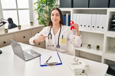 İspanyol doktor elinde kırmızı kurdele ile kendini mutlu ve gururlu olarak gösteren bir kadını işaret ediyor. 