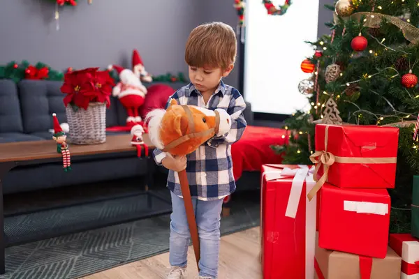 可爱的小男孩在家里的圣诞树旁玩马玩具 — 图库照片