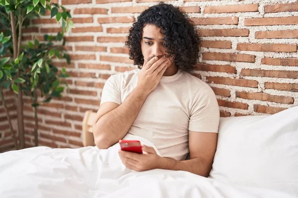 Hispanic Man Curly Hair Using Smartphone Sitting Bed Covering Mouth — Stock Photo, Image