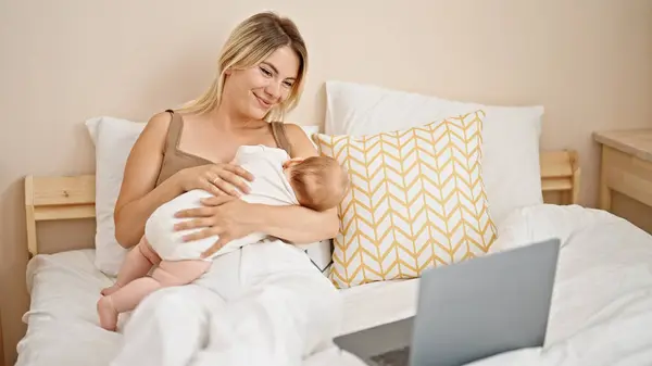 Anne Kızı Yatakta Oturup Bebeği Emziriyorlar Yatak Odasında Dizüstü Bilgisayardan — Stok fotoğraf